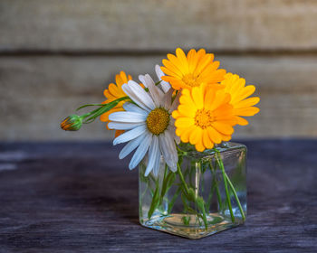 Summer bouquet with chamomiles and calendula in a glass jar on the table of a country house