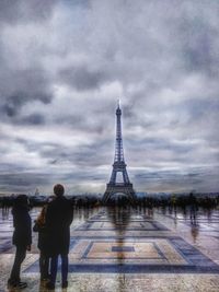 Rear view of people walking on tower against cloudy sky