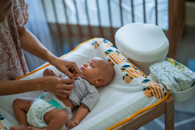 Midsection of baby boy lying on bed at home