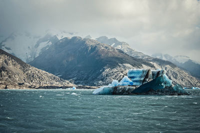 Icebergs in sea with mountain range in background