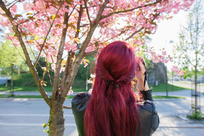 Rear view of woman standing against tree