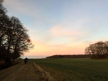 Silhouette man walking on road against sky during sunset