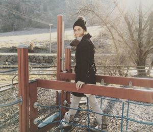 Portrait of young woman standing amidst railing