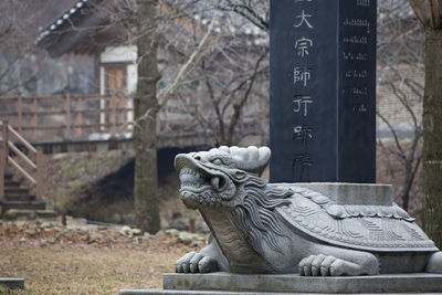 Dragon statue by information sign on field