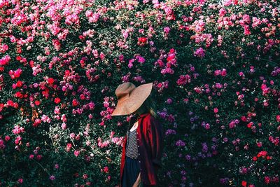 Woman wearing hat while standing against flowering plants at park