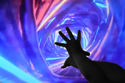 Close-up of silhouette person hand on illuminated light