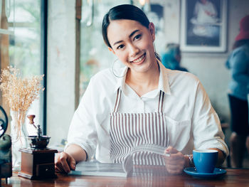 Portrait of smiling woman with magazine in cafe