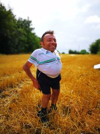 Portrait of man standing on field against sky