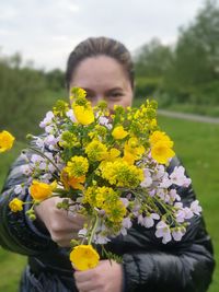 Portrait of young woman holding yellow flowering plant