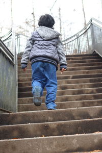 Rear view of boy walking on stairs