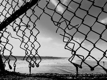 Scenic view of sea seen through chainlink fence