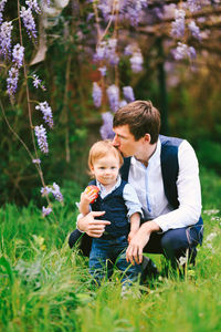 Rear view of father and son on flowering plants