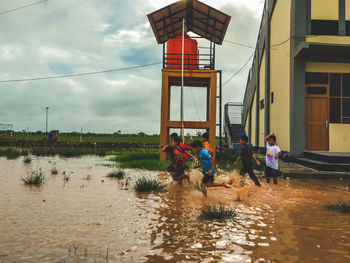 Boys in muddy water against tower