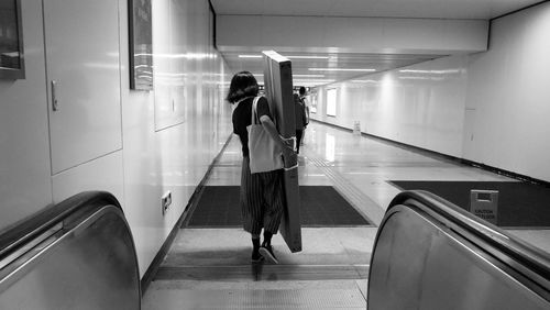 Rear view of people walking on escalator