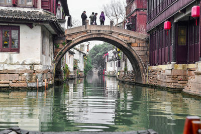 Arch bridge over canal amidst buildings in city