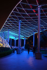 People at illuminated built structure at night