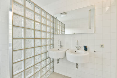 Sink on tiled wall in empty modern bathroom