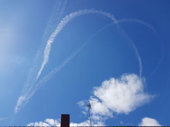 Low angle view of vapor trails against blue sky