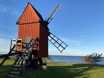 Traditional windmill on beach against sky