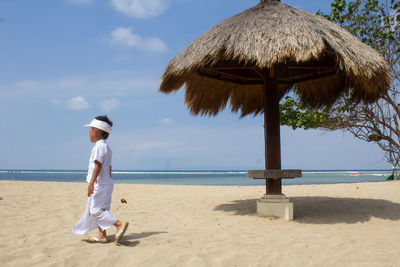 Side view of boy walking at beach against sky