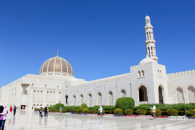 Group of people in front of building mosque against blue sky