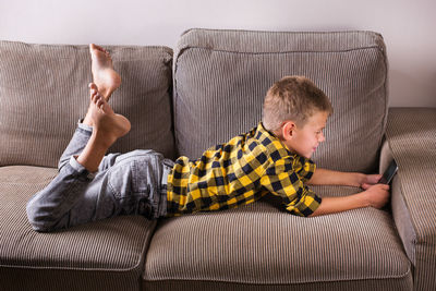 Rear view of boy sitting on sofa at home