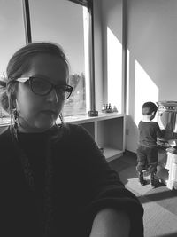 Girl looking away while sitting on window at home