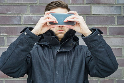 Portrait of mid adult man using mobile phone against wall