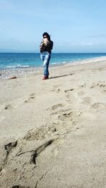 Woman photographing through mobile phone at beach