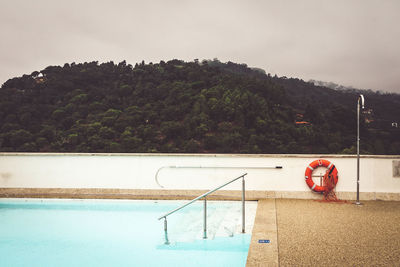 Swimming pool by mountain against sky