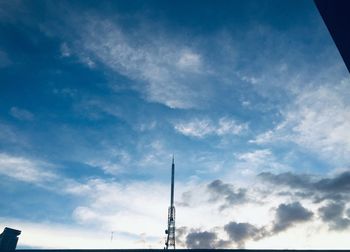 Low angle view of silhouette communications tower against sky