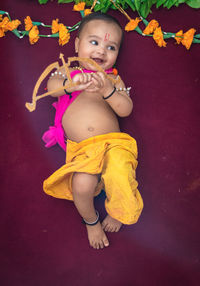 Cute indian boy dresses as lord rama with bow and flowers from top angle