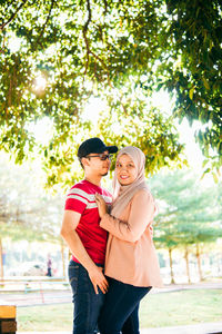 Young couple standing against trees