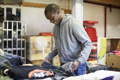 Happy mid adult male volunteer examining fabric at warehouse