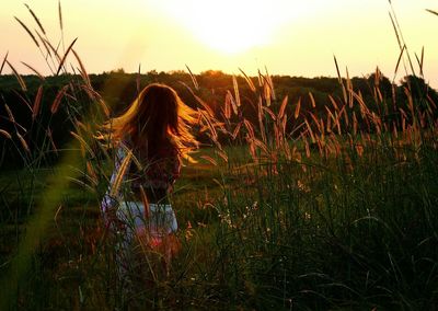 Woman standing on field against sky during sunset