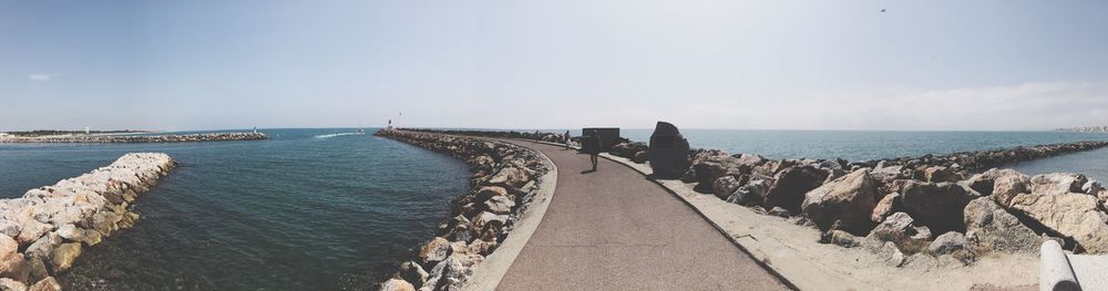 Panoramic view of road amidst sea against sky during sunny day