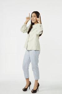 Portrait of smiling young woman standing against white background