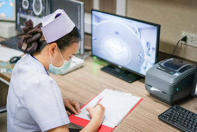 Nurse writing in paper at table in hospital