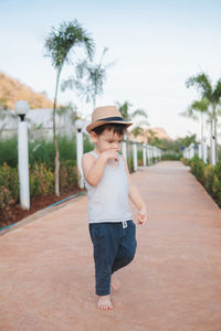 Boy wearing hat standing against plants