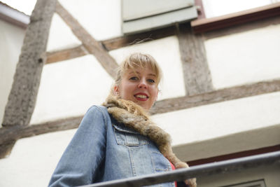 Low angle portrait of smiling woman standing outdoors