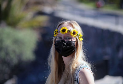 Portrait of young woman wearing mask and wreath outdoors