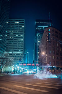 Light trails on road against buildings in city at night