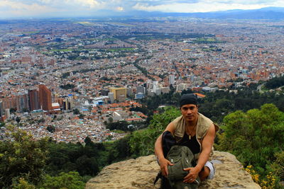 Young man looking at cityscape against sky