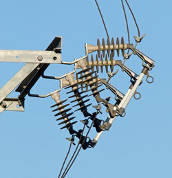 Low angle view of telephone pole against clear blue sky