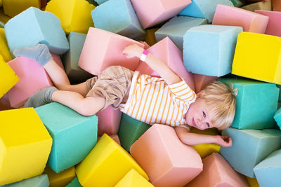 Cute child boy plays with soft cubes in the dry pool in play center