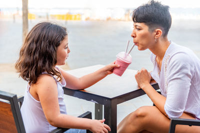 Mother and daughter having fun drinking milkshake