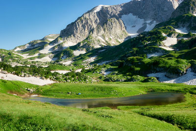 Scenic view of lake by mountains against sky