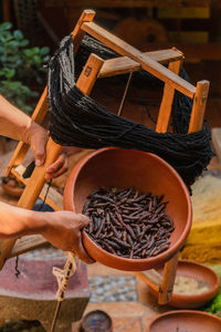 Hand holding bowl of natural ingredients for natural dyes at textile factory.