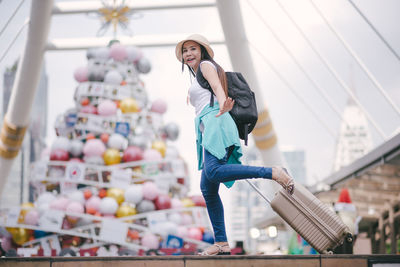 Tourist with luggage standing on steps in city during christmas