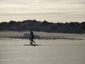 Rear view of man walking on beach against sky